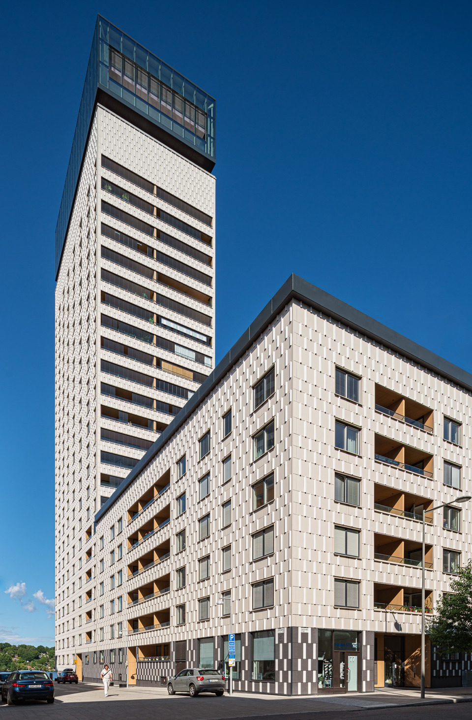 Flerbostadshus med ett mörkt rakt plåttak.